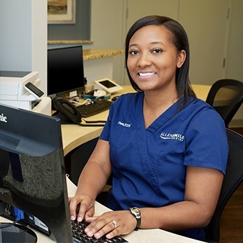 Smiling dentistry team member at dental office reception desk