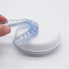 A dentist holding a transparent nightguard over its case