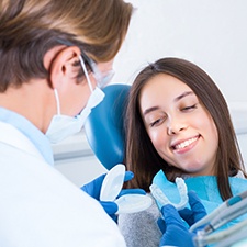 A male dentist explaining how a nightguard works to his female patient