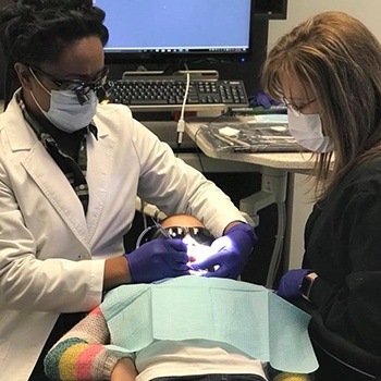 Child receiving dental checkup from Dr. Lewis