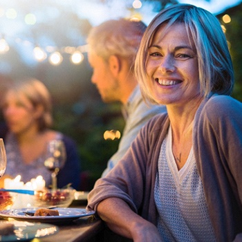 Woman with dental bridge in Allen smiling at dinner party