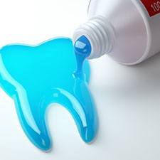 blue toothpaste spilling out into the shape of a tooth 