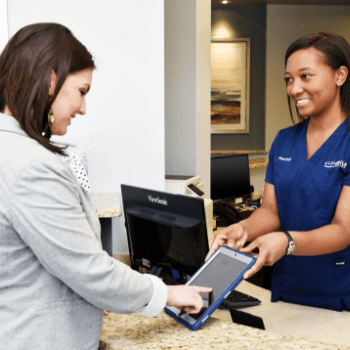 Dental patient paying for emergency dentistry at reception desk