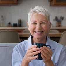 Woman smiling while holding a mug of coffee