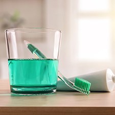 Green mouthwash, toothbrush, and toothpaste sitting on countertop