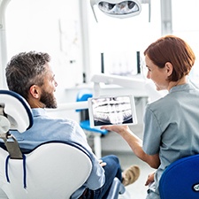 Dentist showing patient X-ray during dental implant consultation