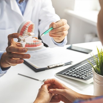 Dentist showing dentistry patient a dental implant model