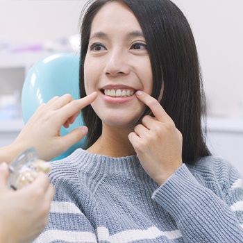 Woman in dental chair discussing how dental implants work with dentist