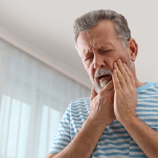 Man rubbing chin while recovering from surgery after dental implants in Allen, TX