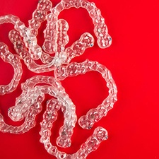 several clear aligners in front of a red background 