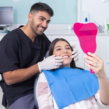 Teen dental patient holding mirror and smiling