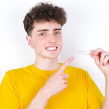 Teenage boy pointing at his Invisalign aligner