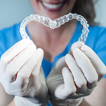 dentist holding Invisalign aligners up in the shape of a heart