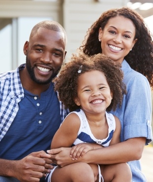 Mother father and child smiling outdoors smiling