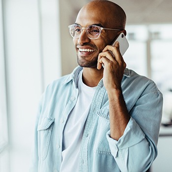  a man wearing glasses holding a phone up to his ear
