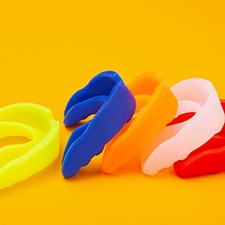 Several ready-made mouthguards in various colors with orange background