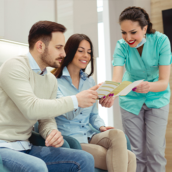 Dental team member talking to man and woman about preventing gum disease