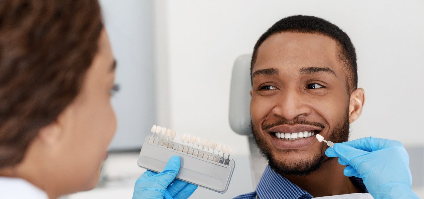 dentist in Allen matching the color of a patient’s tooth to a color chart