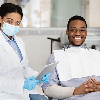 Male patient smiling next to female dentist
