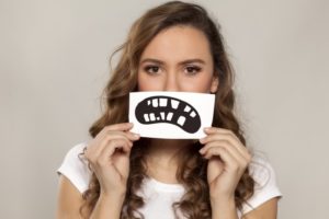 Woman holds picture of unhealthy frown in front of her face