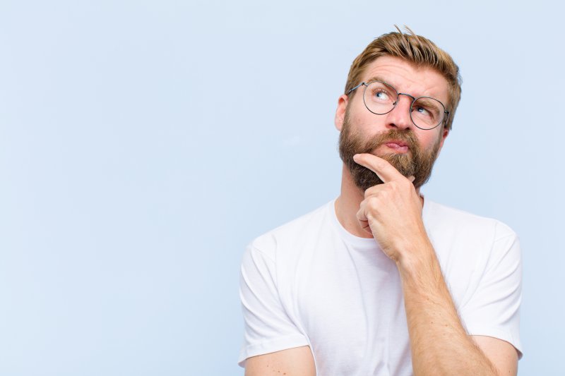 young man wondering whether to choose teeth whitening or porcelain veneers