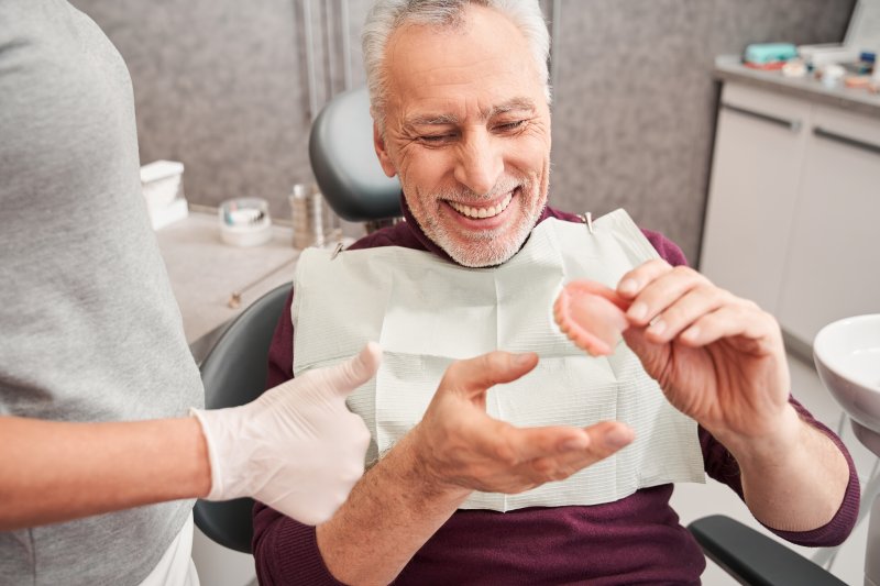A dentist showing dentures to a smiling older man