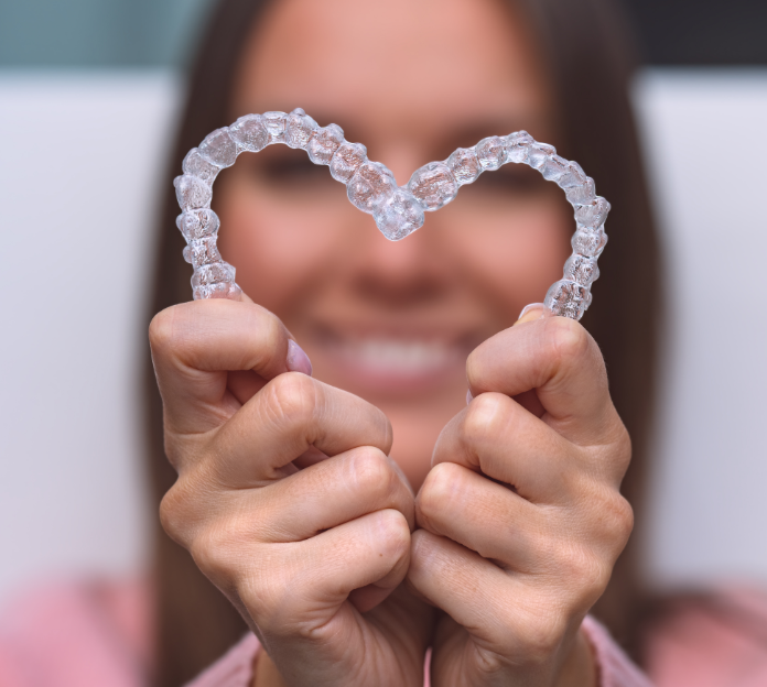 Woman holding clear aligners in a heart shape