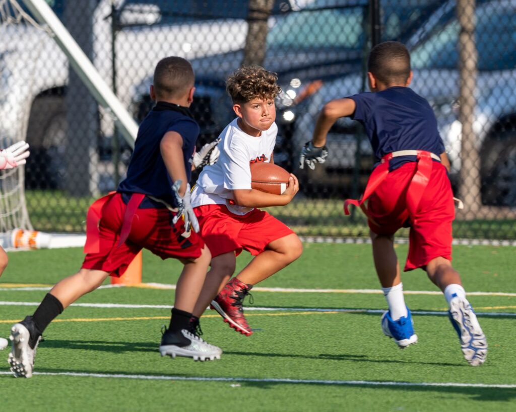 Boys in uniforms playing football on outdoor field