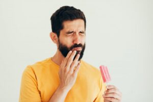 Man wincing from eating cold popsicle. 