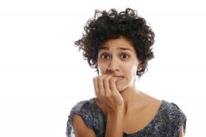 Worried-looking woman chewing on her fingernails.